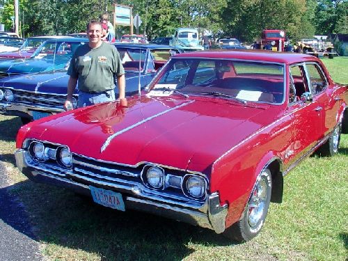 A smiling AJ with a classic muscle car